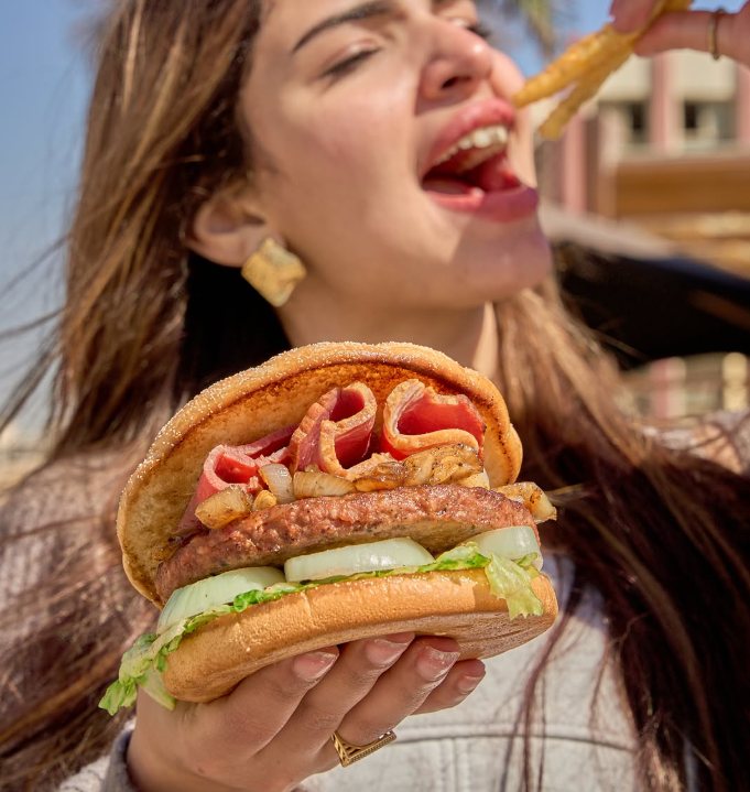 A customer biting into a fresh Dahia burger