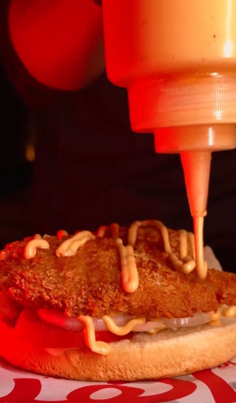 Signature sauce drizzling on a crispy chicken patty